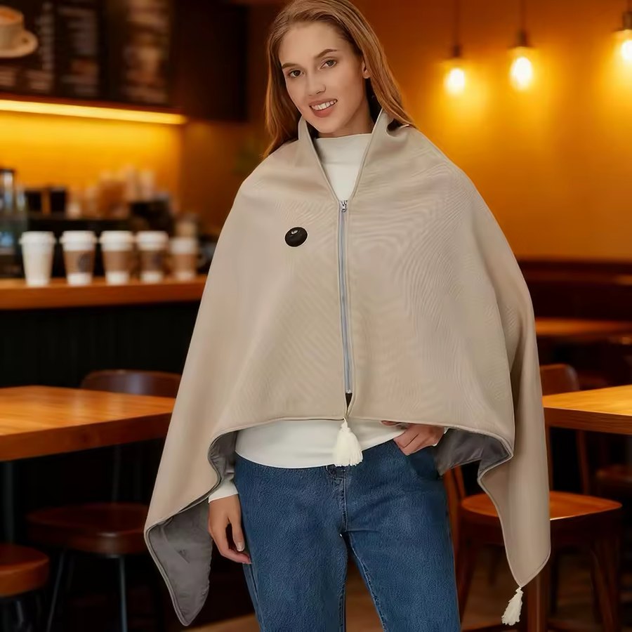 Snuggle Cloak heated hooded sweater worn in a cafe, oat colourway